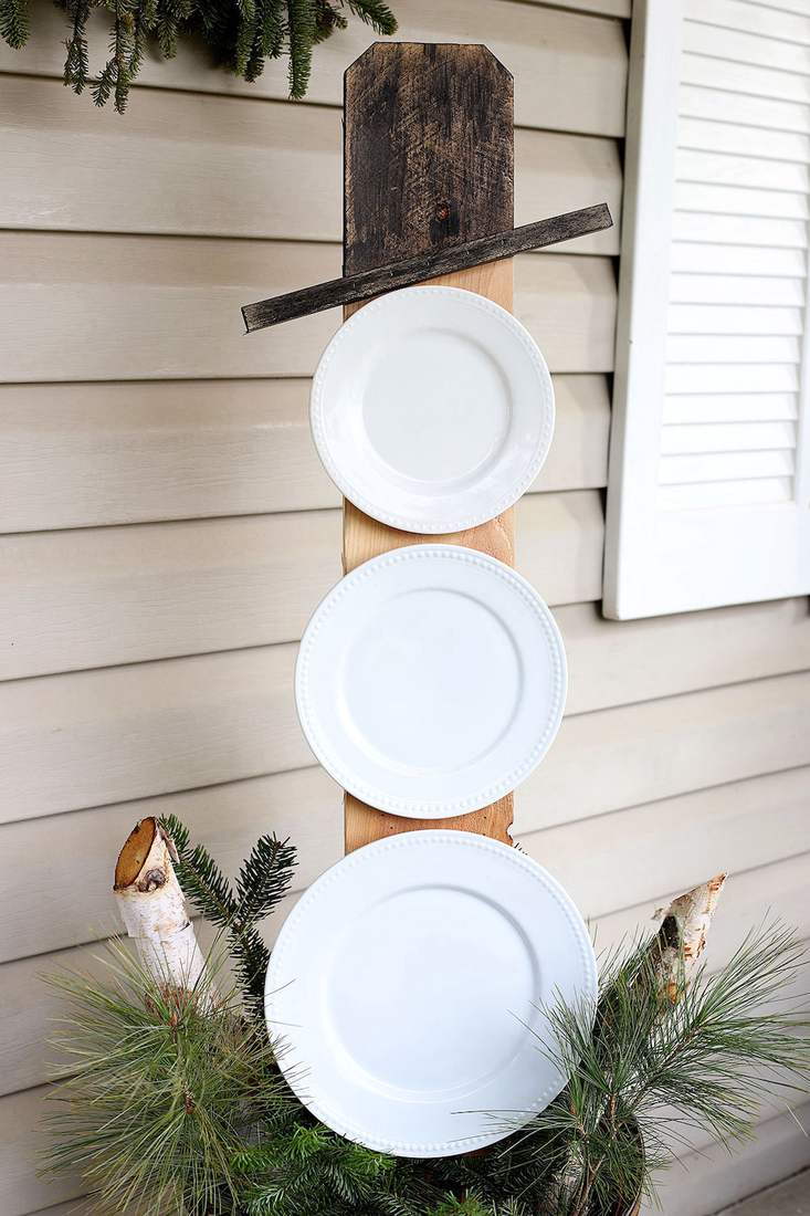 A creative snowman made of white plates hanging as outdoor christmas decorations.