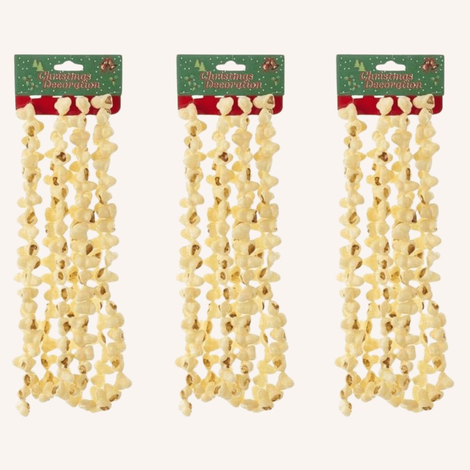 Dried popcorn garlands hanging on a white wall next to a framed vintage holiday print.