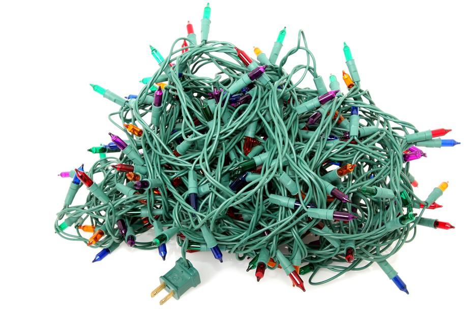 A giant tangled mess of green christmas light cords being pulled forcefully before decorating.