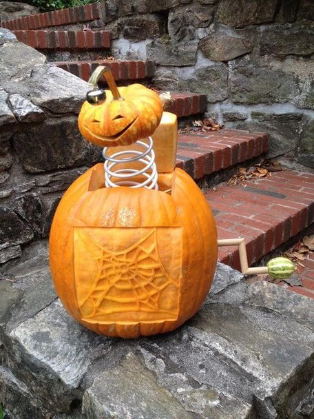 Kitchen island with multiple funny-faced pumpkins, bright lighting, stone countertops.