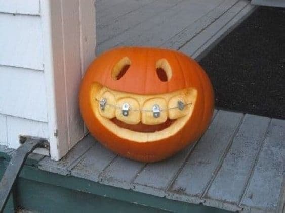 Porch area with pumpkins in a wooden crate, hay, rustic lanterns.