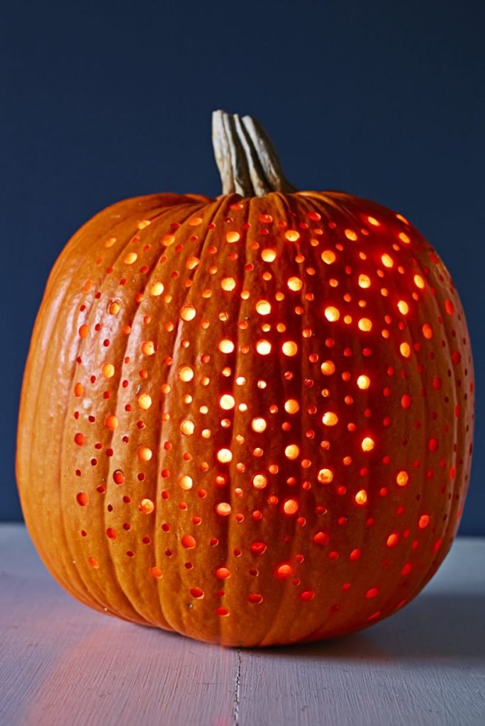 Darkened bedroom with a drill-hole galaxy pumpkin, cozy blankets, ambient lighting.