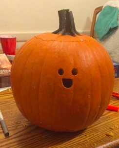 A pumpkin carved with the word Autumn in a modern calligraphy font.