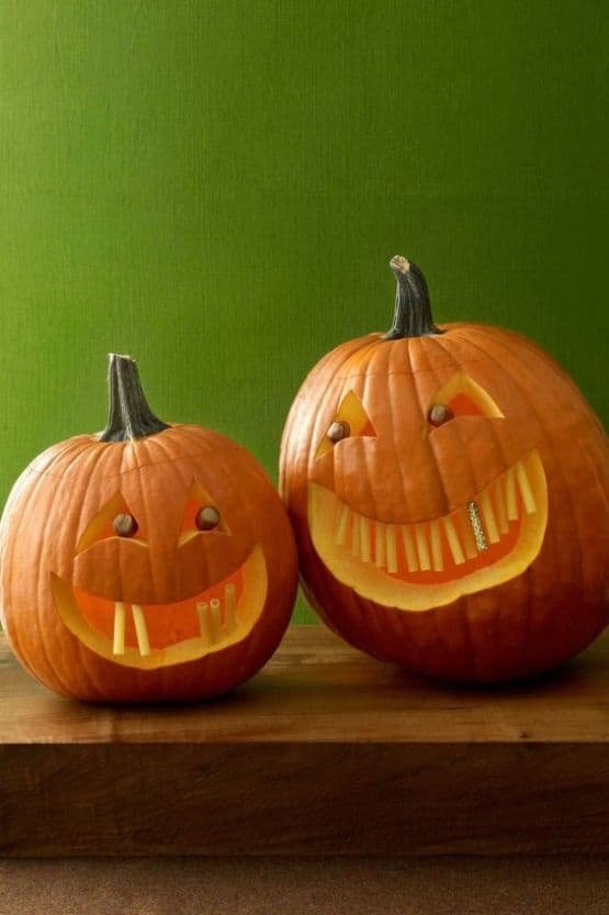 A pumpkin carved with a layered mountain range silhouette on a wooden mantelpiece.