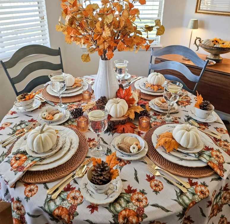Modern kitchen, pumpkin‑print fabric napkins, matte black plates, copper cutlery, warm white pendant lighting