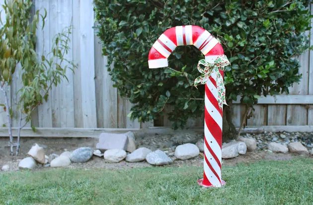 Glowing oversized candy canes made from PVC pipe lining a path as outdoor christmas decorations.