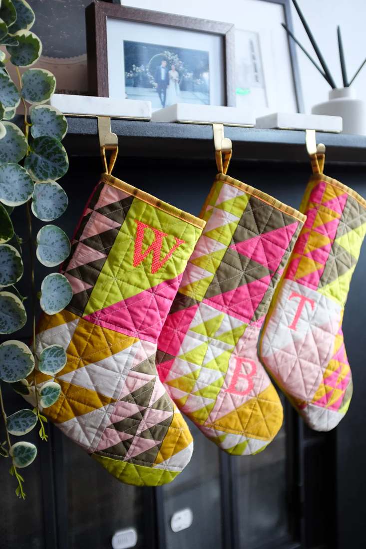 Fireplace mantel, quilted stockings, embroidered initials, warm firelight