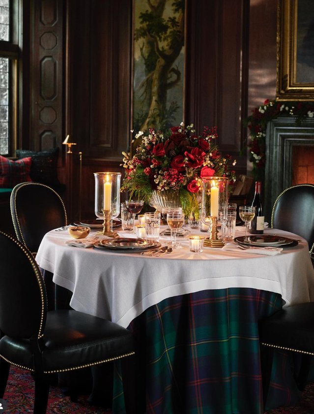 Dining table set with ivory china, gold flatware, deep green velvet runner, soft candlelight.
