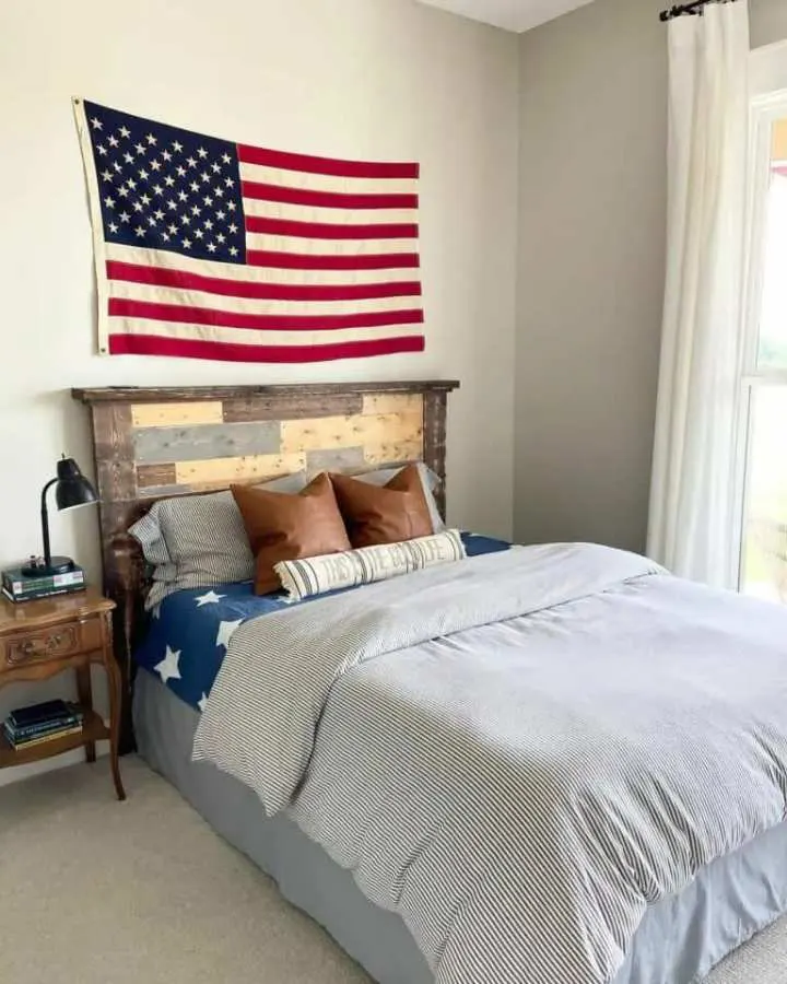 Reclaimed wood headboard beneath a flag display, creating a patriotic focal point in a masculine bedroom.
