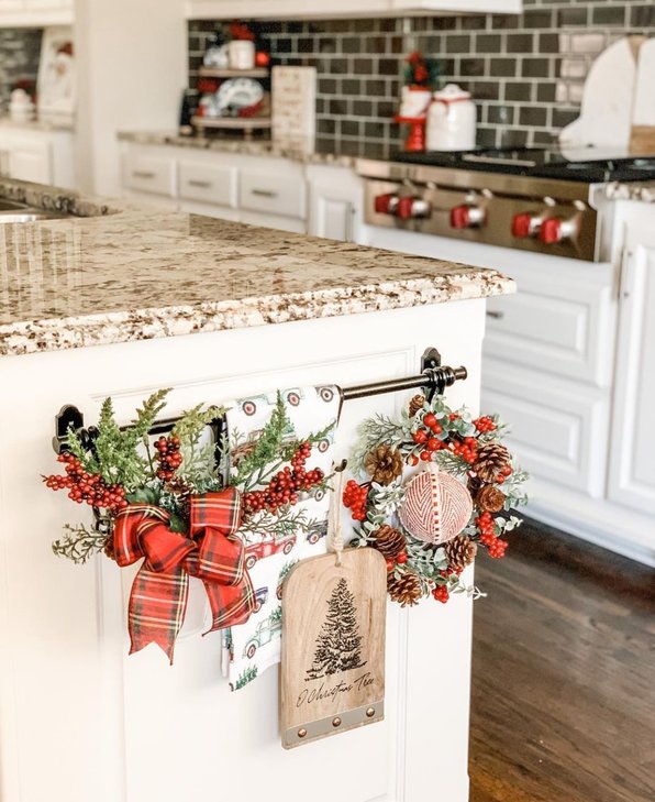 Small red velvet bows attached to the handles of white kitchen cabinets.