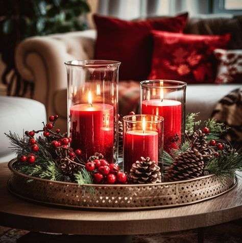 Close‑up of red glass votive candles with gold flecks, set on a dark wooden tray with tiny pinecones.