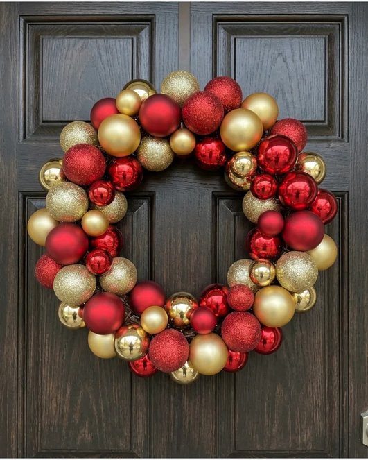 Red gold bauble wreath on dark door with bright lighting