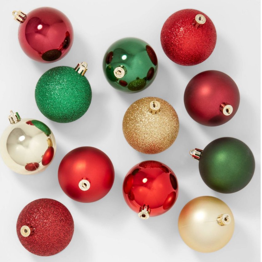 Assorted red, gold, and green glass ornaments clustered on a tree branch with warm lighting.