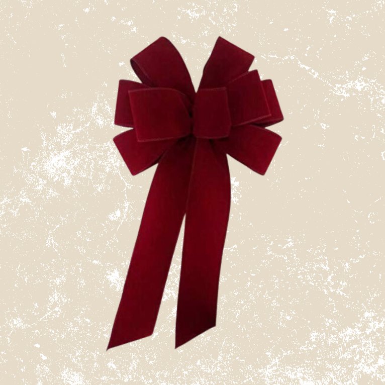 Large red velvet bow hanging on a door handle with a gold bell charm.