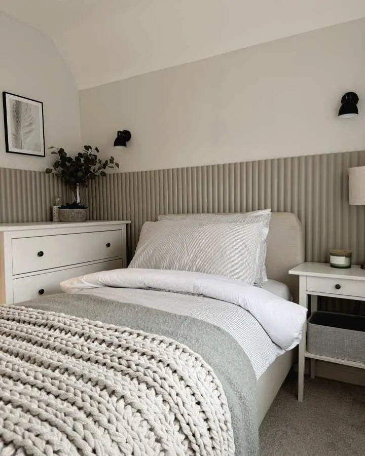 Ribbed upholstered headboard paired with soft neutral bedding and subtle lighting in a modern bedroom.