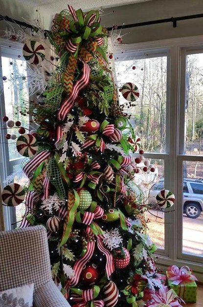 Tree wrapped in red and white ribbon with green ornaments and peppermint accents