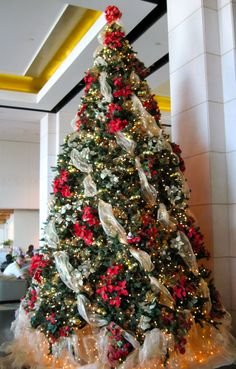 Minimalist great room showing ribbon wrapped christmas tree near oak floor in warm spotlighting