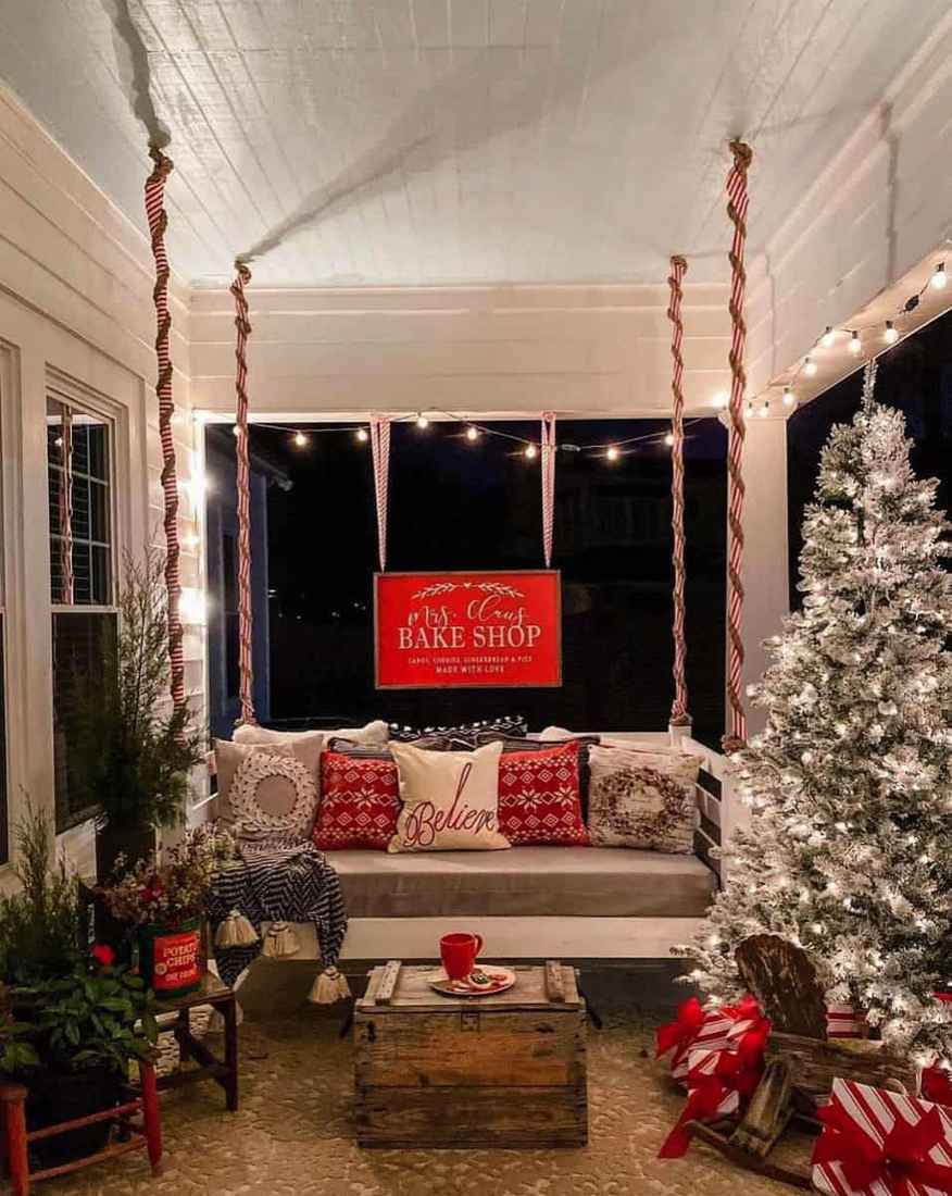 A rustic porch decorated with wooden crates, lanterns, and greenery as outdoor christmas decorations.