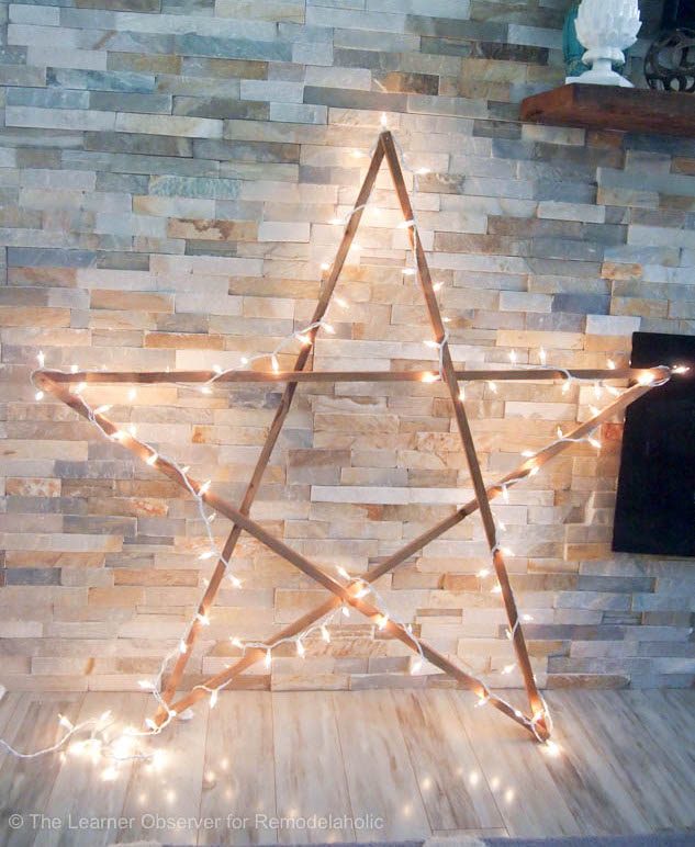 Large wooden stars wrapped in fairy lights hung as outdoor christmas decorations.