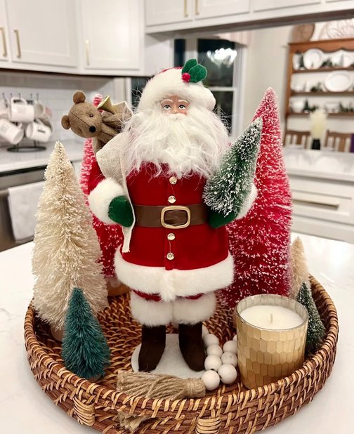 Wicker basket with a bottle brush tree and Santa figurine on the counter.