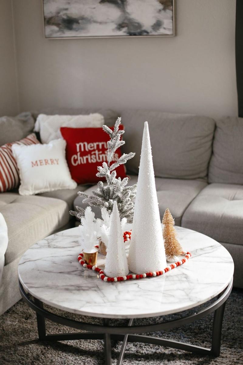 Minimalist Scandinavian Christmas coffee table decor featuring slender tapers, simple sprigs, and white ceramics.