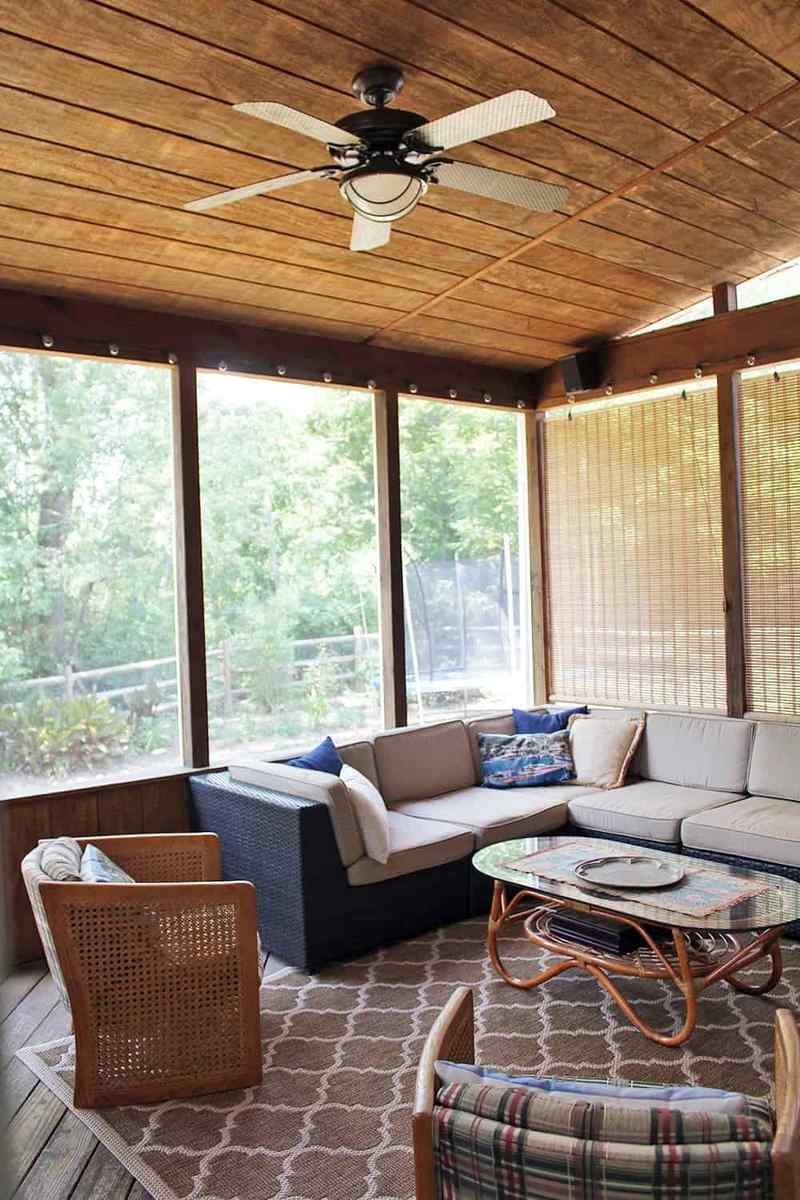 Screened in porch with a navy blue sectional sofa, industrial ceiling fan, and modern decor.