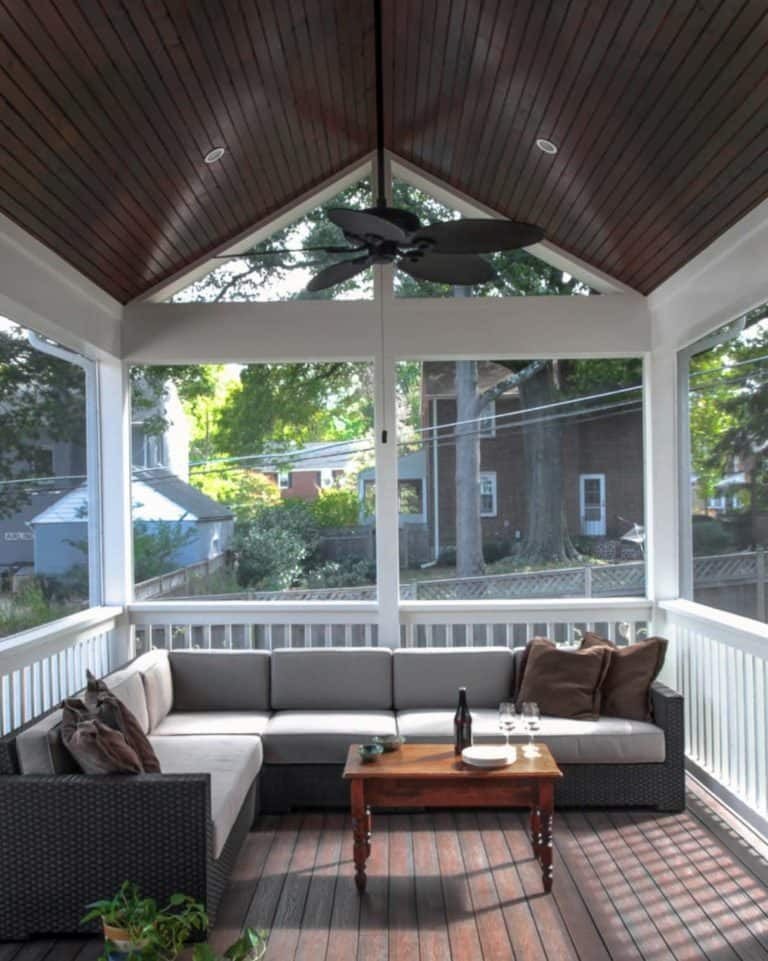 Screened in porch with a red brick fireplace, mounted television, and comfortable lounge seating.