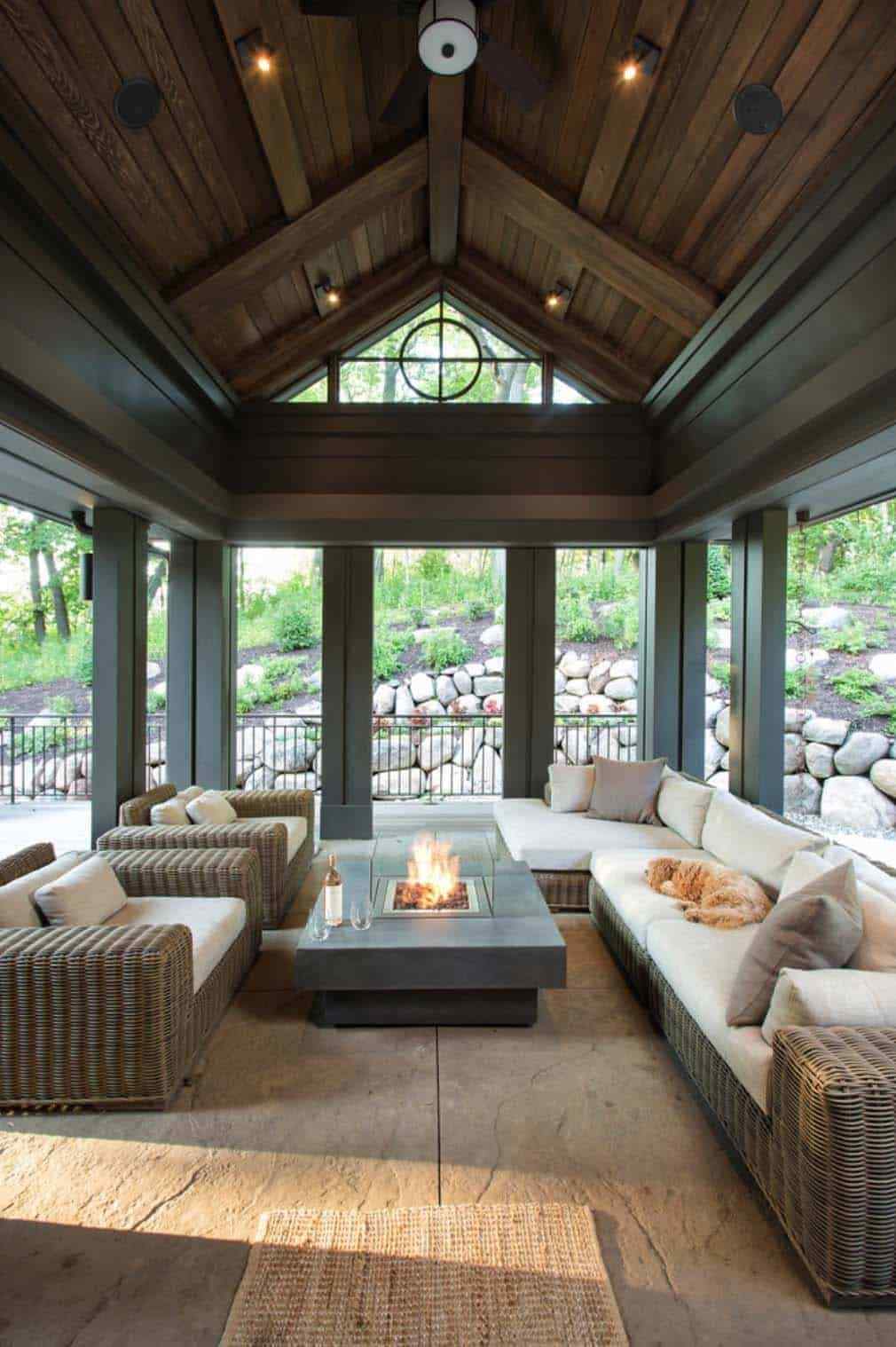 Screened in porch featuring a charcoal gray sectional, dark wood accents, and moody lighting.