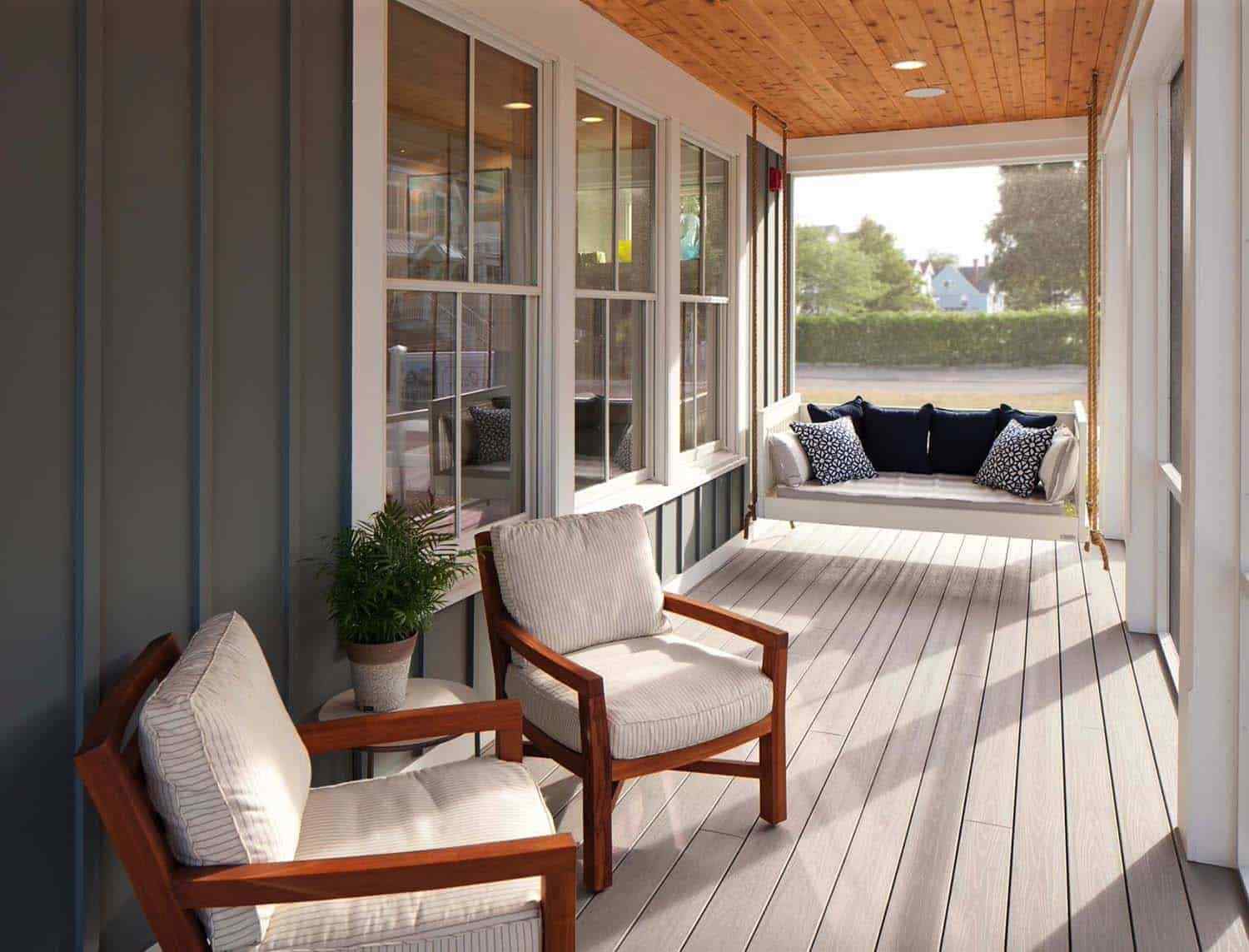 Screened in porch featuring a cozy fireplace, vibrant red flowers, and comfortable lounge chairs.