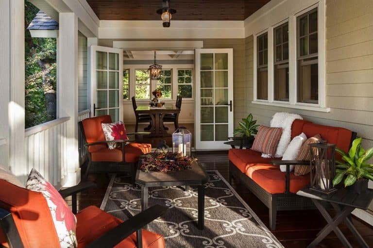 Screened in porch with striking orange-red chairs, neutral rug, and modern decor.
