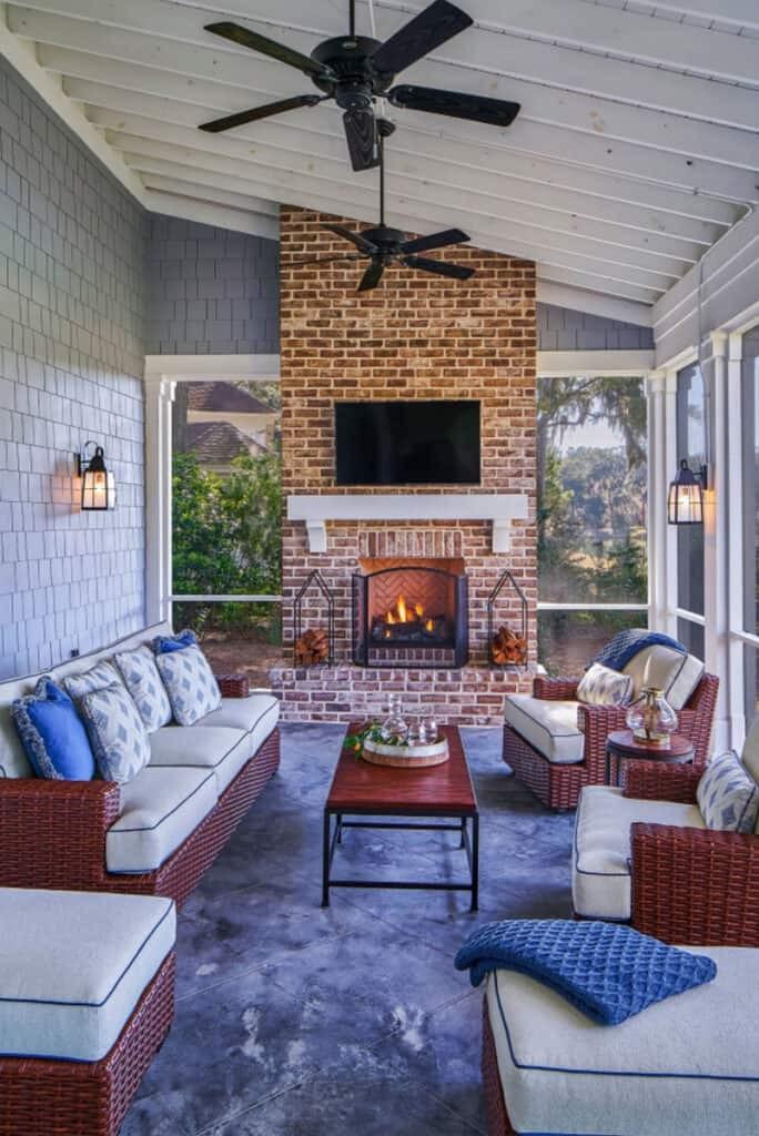 Screened in porch with a fireplace, pink accent pillows, and cozy seating.