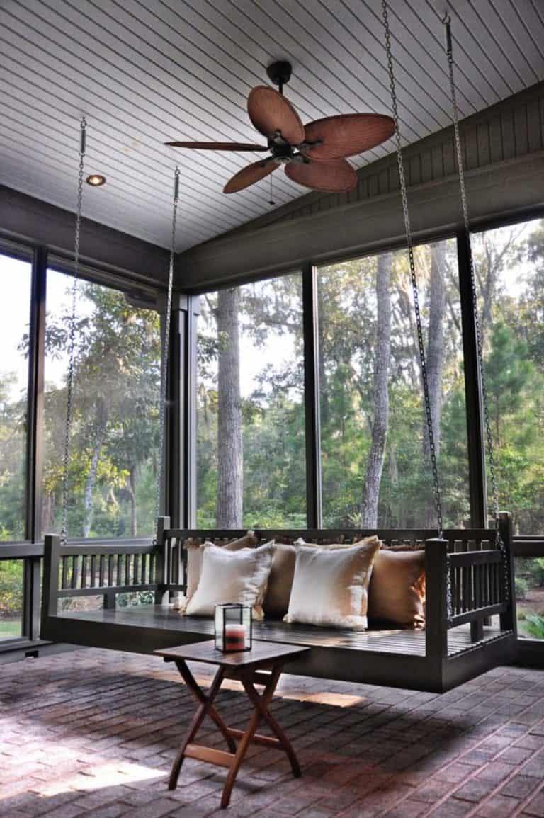 A screened in porch ideas porch swing fan setup with comfortable cushions and ceiling breeze.