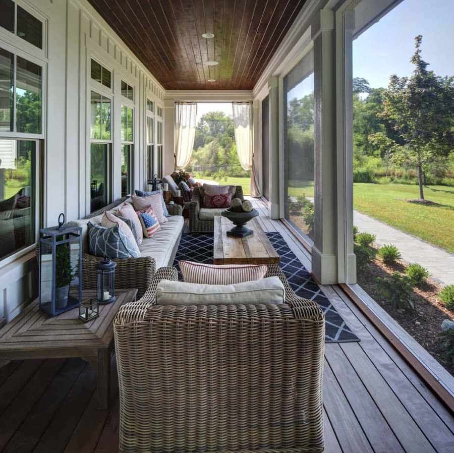 Screened in porch ideas stone fireplace with rustic appeal and comfortable lounge furniture.