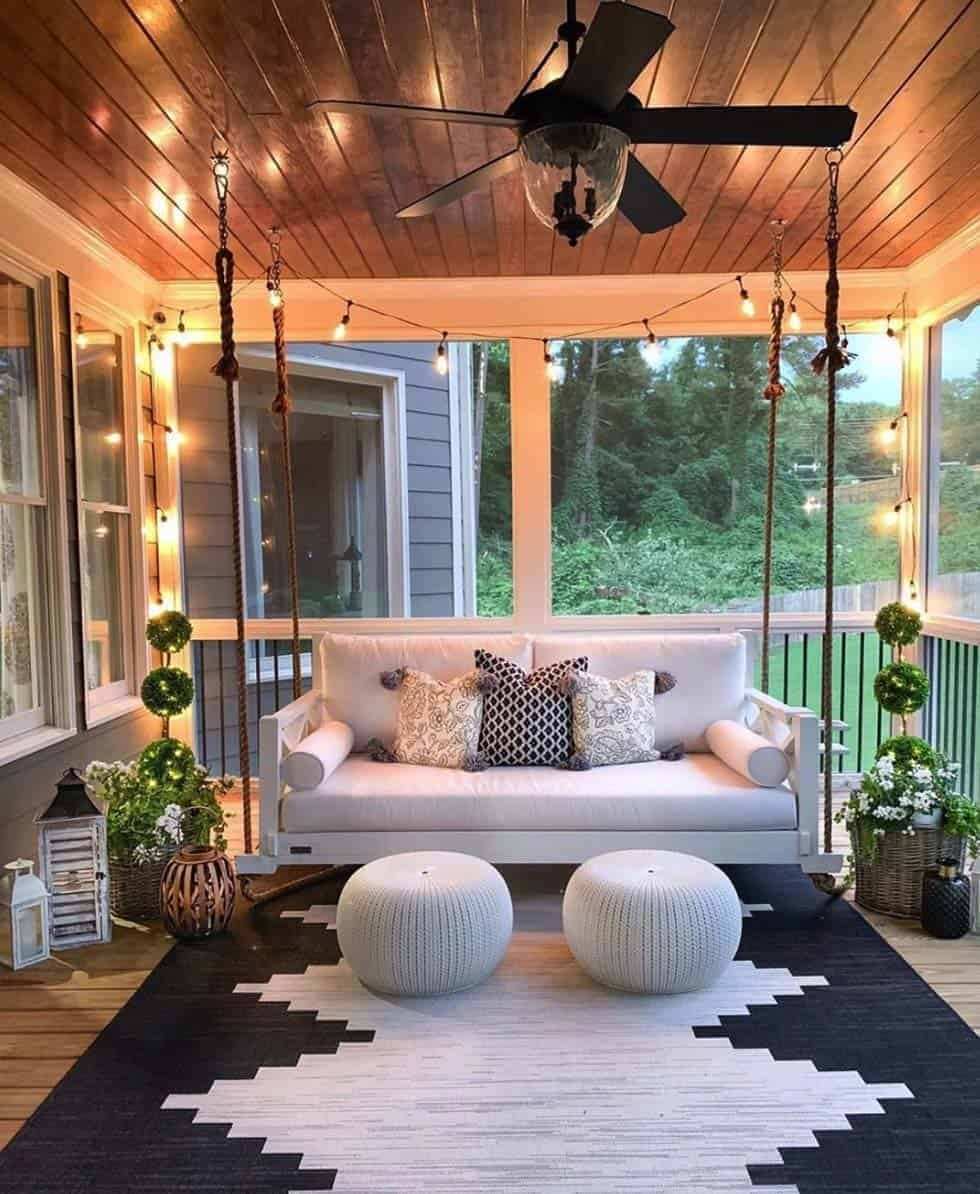 Screened in porch ideas swing string lights fan creating a magical evening outdoor atmosphere.