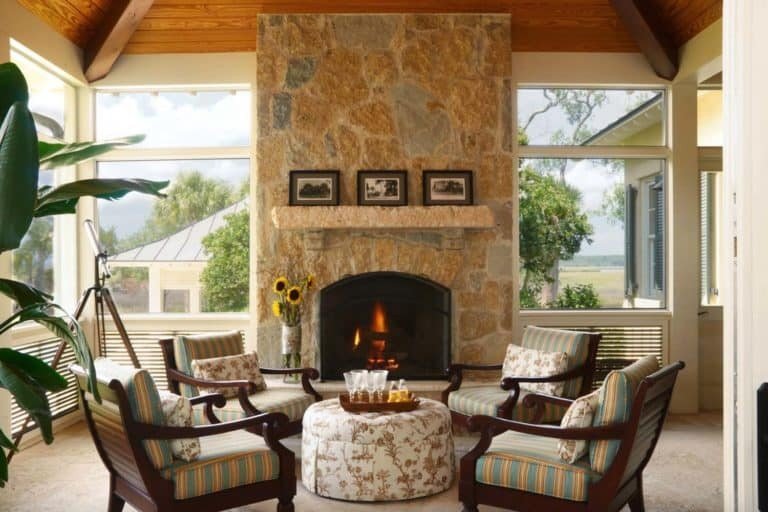 Screened in porch ideas wicker chandeliers hanging over a cozy lounge and dining space.