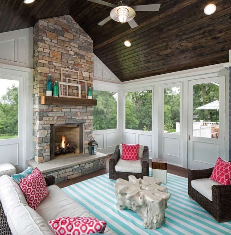 Screened in porch ideas wicker striped rug fireplace with a classic and cozy design layout.