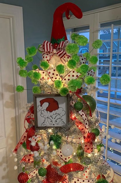 Tree with silver tinsel and green ornaments in a bright room