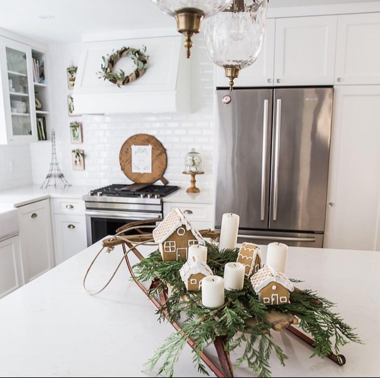 Wooden sled filled with greenery and pinecones on the kitchen island.