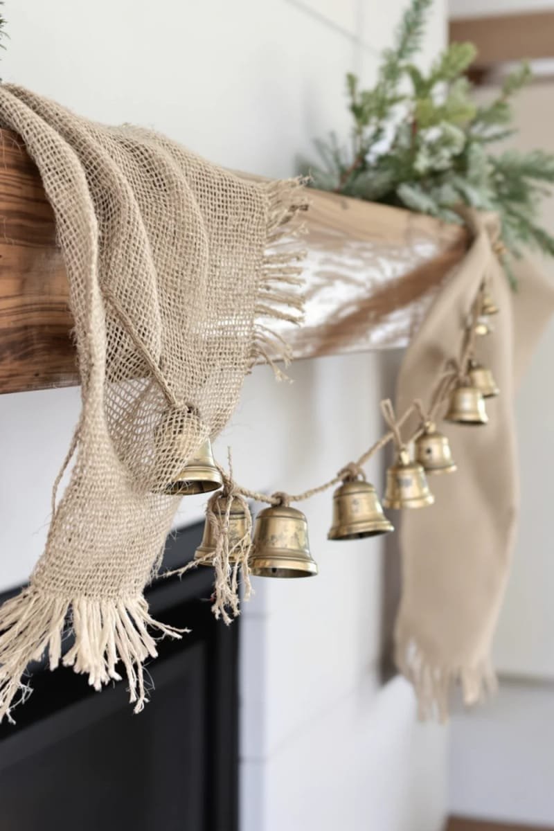 Rustic mantel with a burlap garland adorned with silver sleigh bells and twine.