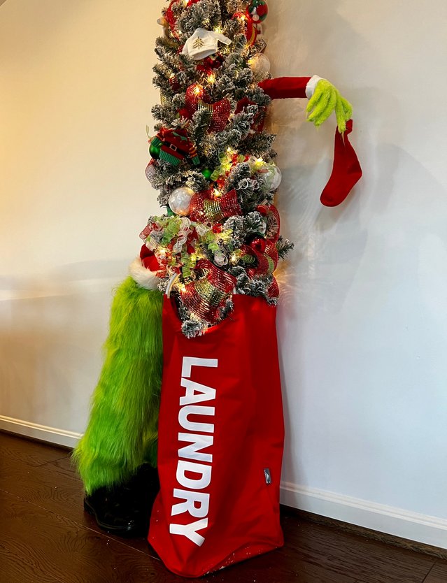 Slim flocked tree with a green Grinch arm reaching out in a narrow space