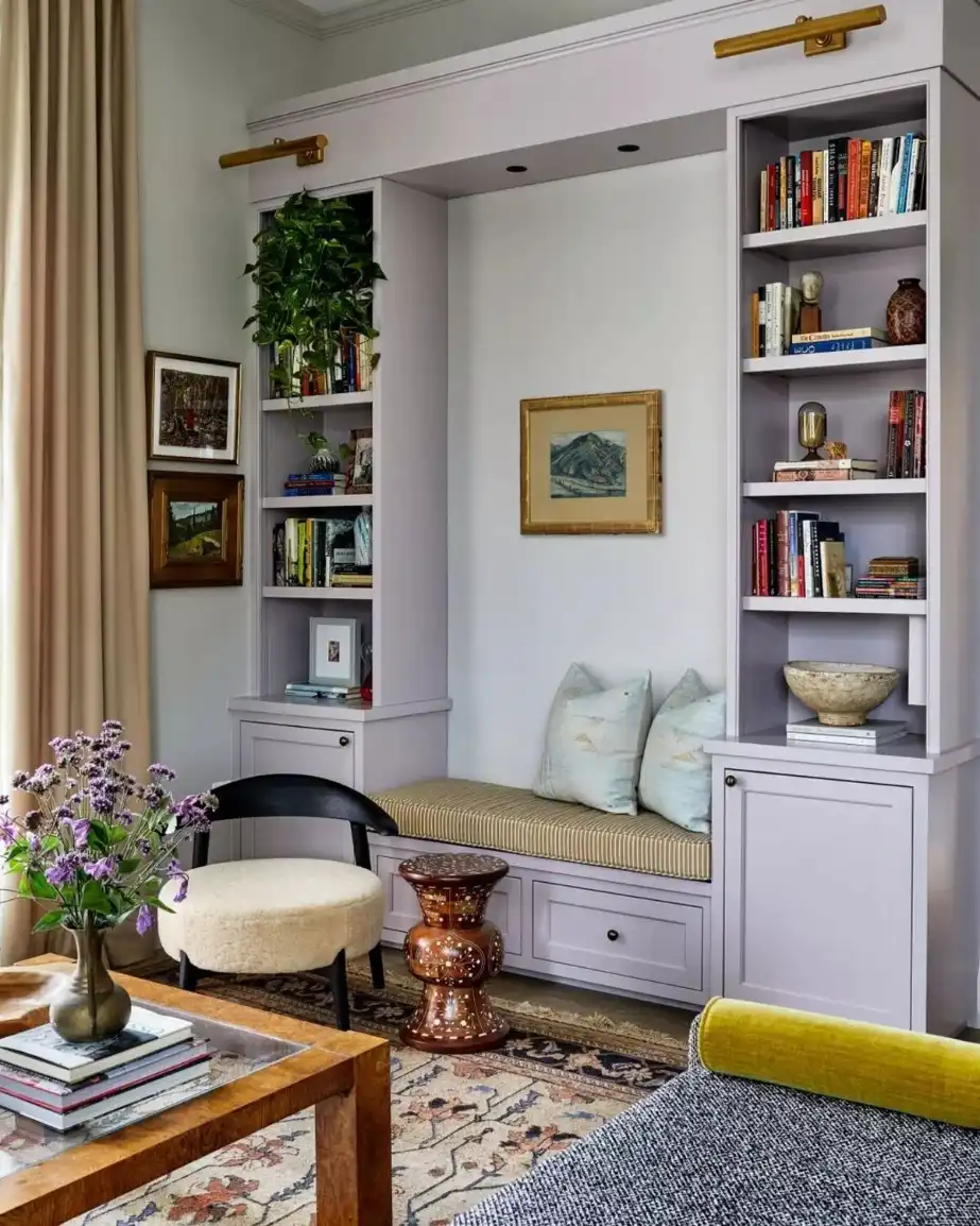 Small living room with built-in reading nook, bookcase, cushioned bench, and warm pendant lighting.