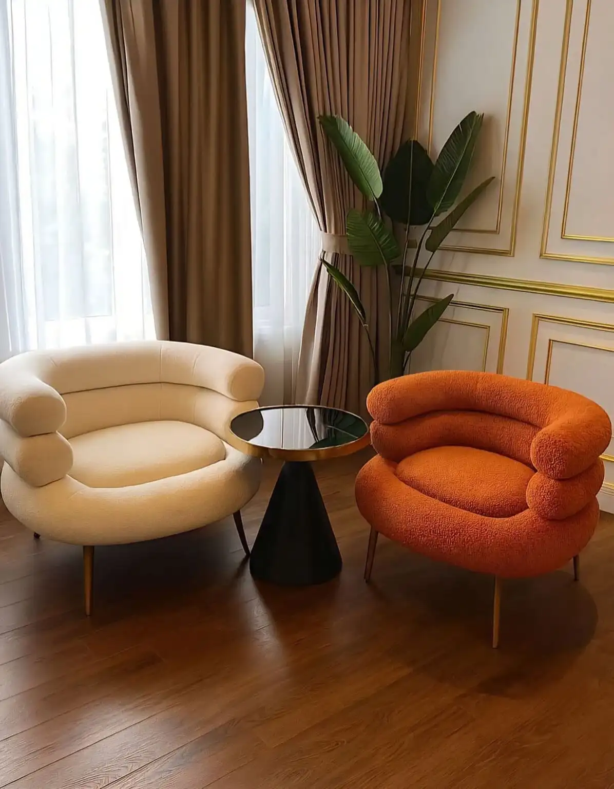Small living room with two curved boucle accent chairs, terracotta vase, and soft natural light.