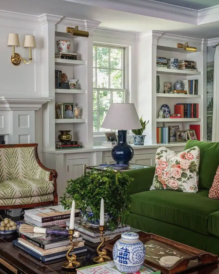 Small living room with emerald green velvet couch, white floating shelves, and warm ambient lighting.