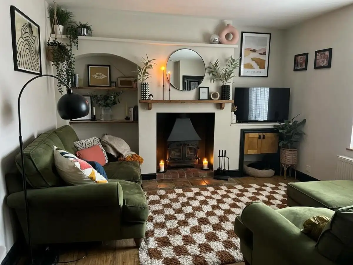 Small living room with green velvet sofas, black and white checkerboard rug, and warm lighting.