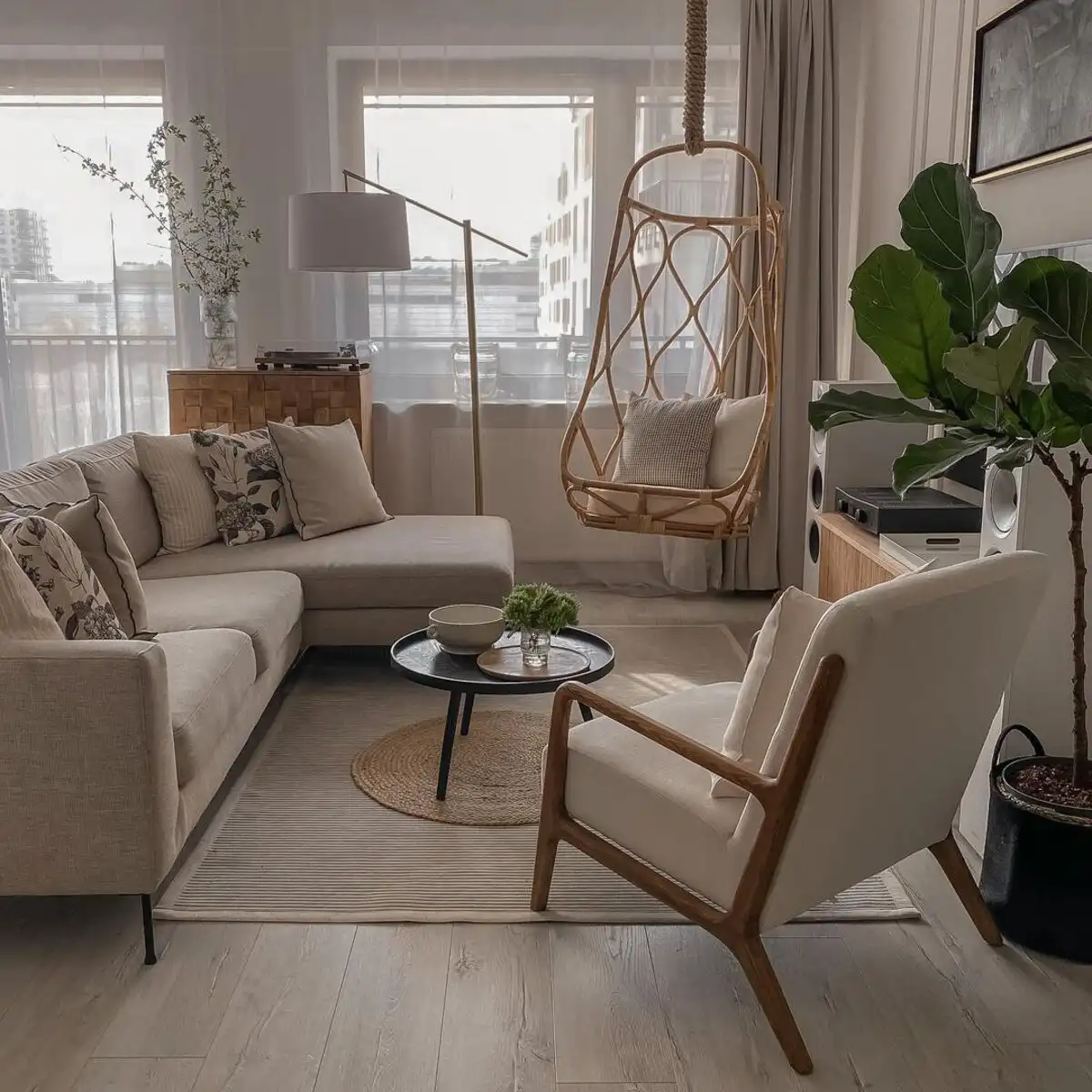 Small living room with hanging rattan swing chair, beige sofa, and natural light from a large window.