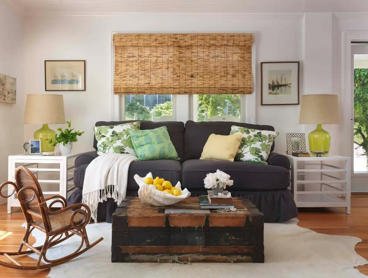 Small living room with vintage trunk coffee table, charcoal sofa, and warm lighting in a cozy, rustic setting.