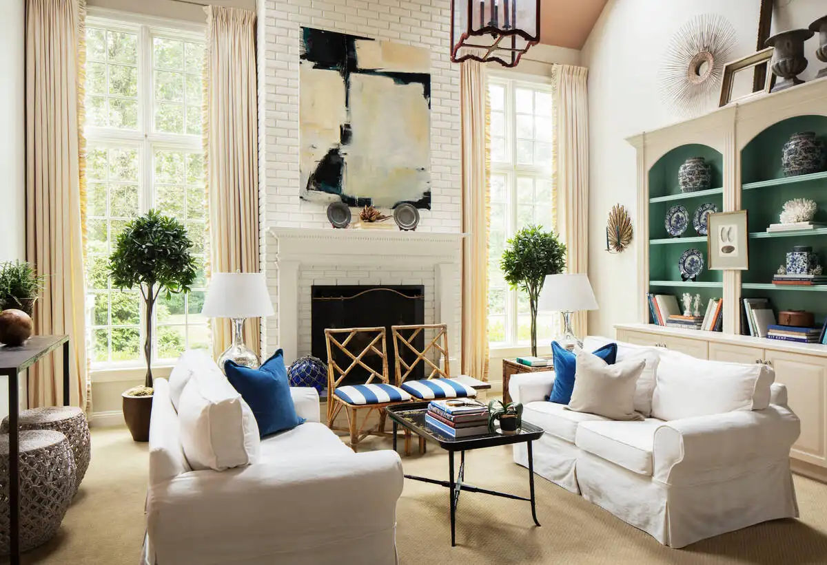 Small living room with white brick fireplace, built-in bookcase, and white sofa in bright natural light.