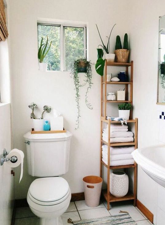 Minimalist white bathroom featuring a bamboo storage tower, floating vanity, glass shower enclosure, and soft LED lighting.