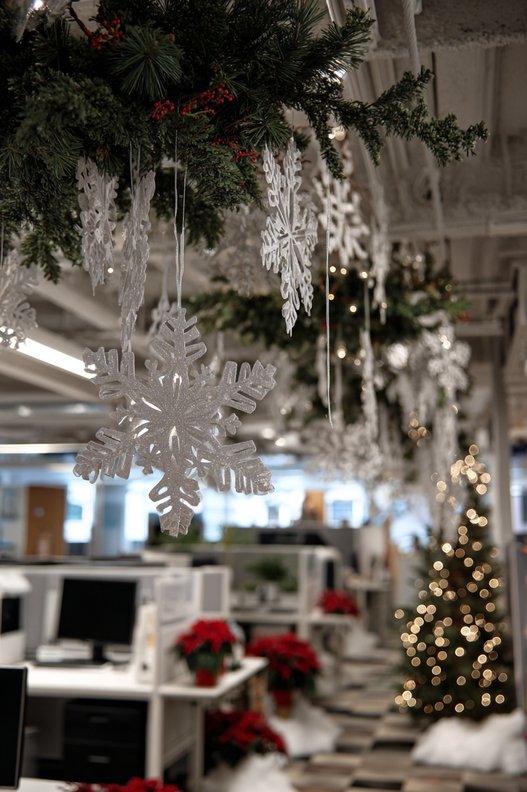 Large cutout paper snowflakes taped to a frosted glass window with soft daylight filtering through.
