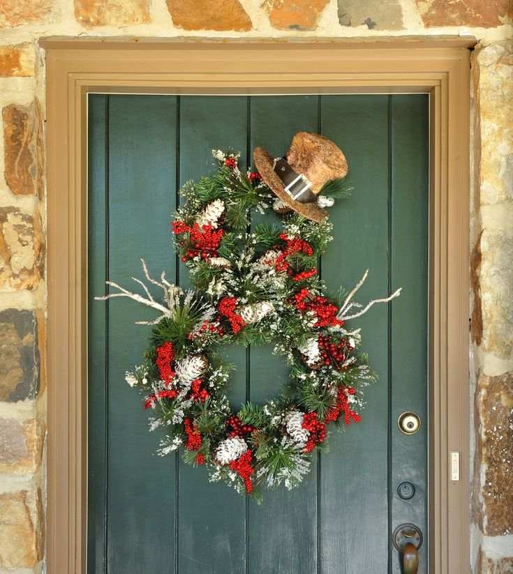 A unique snowman-themed wreath featuring a miniature top hat and frosted pine needles.